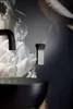 A close-up shot of a bathroom sink and faucet with a floral wallpaper. Produktbild-Vorschau