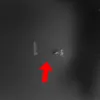 A close-up view of a dark, textured surface with some marks and a red arrow pointing upwards. Produktbild-Vorschau