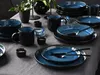 A table setting with blue and black dinnerware, including plates, bowls, and mugs. Produktbild-Vorschau