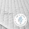 A close-up of a quilted surface with water droplets, featuring a circular marketing graphic. Produktbild-Vorschau