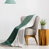 A green and white sherpa blanket draped over a chair next to a plant. Produktbild-Vorschau