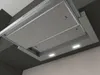 A close-up, angled view of a stainless steel range hood installed under dark cabinetry. Produktbild-Vorschau