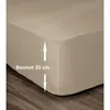 Close-up of a beige fitted sheet corner on a wooden floor, with measurement indicators. Produktbild-Vorschau