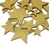 A pile of gold glitter star-shaped decorations scattered on a white background. Produktbild-Vorschau