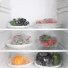 Inside a refrigerator, showing various fruits and vegetables covered in plastic wrap on shelves. Anteprima dell’immagine prodotto