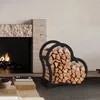 A heart-shaped firewood rack filled with logs is placed next to a modern fireplace. Podgląd zdjęcia produktu