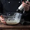 A person in a chef's uniform is using a hand blender to mix ingredients in a glass bowl. Produktbild-Vorschau