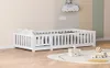 A white wooden children's bed with a railing is set up in a room with pastel-colored walls and a rug on the floor. Anteprima dell’immagine prodotto