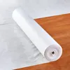 A roll of white fabric protection film is lying on a wooden floor. Anteprima dell’immagine prodotto