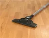 A vacuum cleaner head and part of its extension wand are shown on a wooden floor. Voir les images du produit