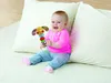 A baby sitting on a floor with pillows and holding a toy. Anteprima dell’immagine prodotto