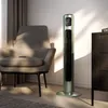 A modern silver tower fan is placed next to an armchair in a well-lit room. Sunlight streams in from the left, casting dramatic shadows on the chair and floor. Produktbild-Vorschau