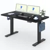 A black adjustable standing desk with two computer monitors, a keyboard, a mouse, headphones, a cup of coffee, and a bag. Náhled obrázku produktu