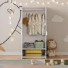 A child's bedroom with an open wardrobe filled with clothes and storage, decorated with wall art and string lights. Anteprima dell’immagine prodotto
