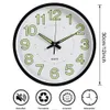 A round wall clock with luminous numbers and hands, shown with icons indicating its features. Voir les images du produit