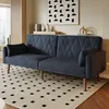 A dark gray sofa with a diamond pattern is shown in a living room setting, placed on a rug with a black and white geometric pattern. A framed abstract artwork hangs on the wall behind the sofa. Voir les images du produit