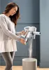 A woman empties dust from a cordless vacuum cleaner into a bin. Anteprima dell’immagine prodotto