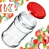 A clear glass jar with a red lid, surrounded by fresh vegetables and herbs. Anteprima dell’immagine prodotto