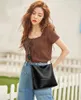 A woman is posing outdoors with a black handbag. Náhľad obrázku produktu
