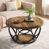 A round coffee table with a wooden top and a black metal base is placed in a living room setting next to a sofa. Anteprima dell’immagine prodotto