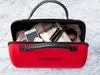 A red travel case filled with personal items like a phone, scarf, and makeup. Produktbild-Vorschau