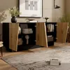 A modern sideboard with open doors, displaying its interior storage and decorative items, in a well-lit room with a rug and artwork. Produktbild-Vorschau