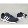 A pair of black Adidas sneakers with white stripes on a light gray concrete background. Produktbild-Vorschau