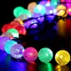Mehrfarbige LED-Lichterkette mit strukturierten kugelförmigen Birnen, in einer Kurve auf dunkler Oberfläche angeordnet Produktbild-Vorschau