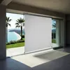 A white vertical awning is partially deployed on a modern patio overlooking a tropical beach scene. Náhled obrázku produktu