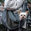 A person carrying a small dog in a sling-style pet carrier. Produktbild-Vorschau