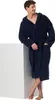 A man wearing a navy blue bathrobe leans against a white cube. Produktbild-Vorschau