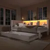 A bedroom scene at night with a daybed and a pull-out trundle bed, featuring built-in shelving with LED lighting. Náhled obrázku produktu