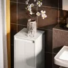 A white bathroom cabinet with a decorative door and a vase with flowers on top, next to a sink. Produktbild-Vorschau