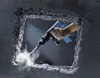 A hand wearing a glove is using a Bosch GSH 11 E SDS Max demolition hammer to break through a concrete wall, creating dust and debris. Produktbild-Vorschau
