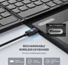 A close-up of a black wireless keyboard being charged via a USB-C cable, with feature callouts. Produktbild-Vorschau