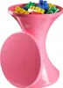 A pink hourglass-shaped stool filled with colorful building blocks. Voir les images du produit