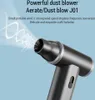 A close-up marketing image of a black and gray dust blower with white air effects emanating from the nozzle. Náhled obrázku produktu