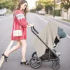 A woman is pushing a stroller on a street. Produktbild-Vorschau