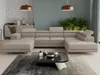 A modern living room with a large U-shaped sectional sofa, coffee table, and plants.
