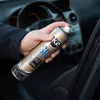 A hand holding a spray can inside a car. Produktbild-Vorschau