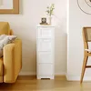 A narrow white cabinet with four drawers stands next to a yellow sofa in a room with wooden floors. Produktbild-Vorschau