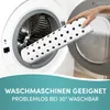 A hand is placing a white, patterned mat into a washing machine. Produktbild-Vorschau