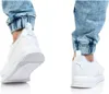 A close-up view of a person wearing white Puma sneakers and acid-washed jeans. Anteprima dell’immagine prodotto