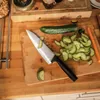 A knife is shown on a cutting board with sliced cucumbers. Podgląd zdjęcia produktu