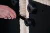 A hand is shown adjusting a black roller on the underside of a cream-colored, corduroy-covered furniture piece. Produktbild-Vorschau