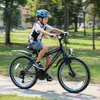 A young boy is riding a bicycle on a paved path in a park. Produktbild-Vorschau