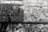 A close-up, angled view of a folded rug with a modern abstract pattern in black, gray, and white. Produktbild-Vorschau