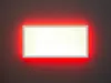 A rectangular LED panel light with a white frame and a bright white illuminated surface, surrounded by a red glow, mounted on a dark gray wall. Produktbild-Vorschau