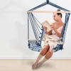 A woman reading a book while sitting in a hanging chair. Produktbild-Vorschau