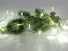A fir branch with white LED lights wrapped around it, set against a white background. Produktbild-Vorschau